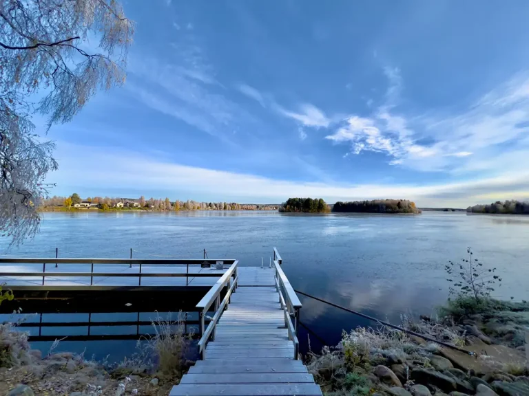 A calm autumn lake in Finnish Lapland, framed by forest in seasonal colour